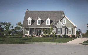 An attractive light gray and dark beige brick house with new roof shingles installed by Paramount Builders