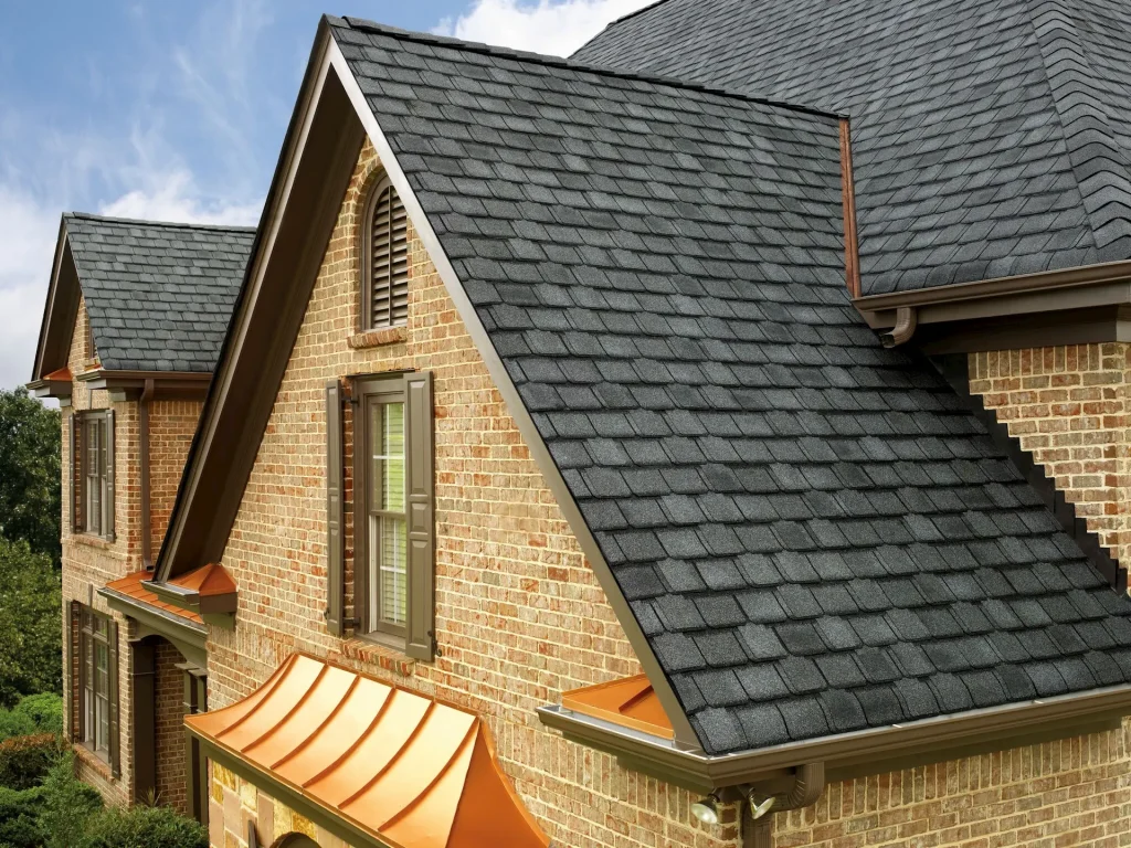 "A brick house with a slate roof and black chimney, designed by Paramount Builders in shades of light orange and dark gray.